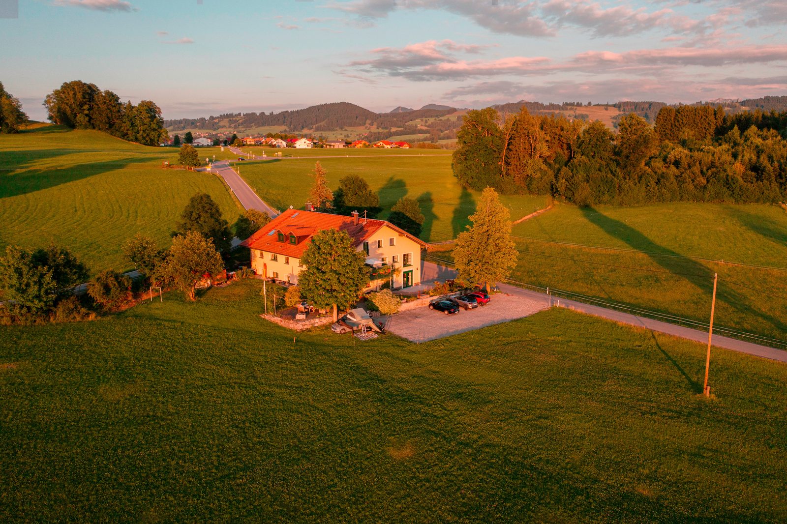 Luftaufnahme unseres Hauses im Allgäu, im Abendlicht, mit Blick auf die Berge